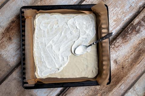 Flammkuchenteig ausrollen und dünn mit dem Schmand bestreichen. (Quelle: Dorn/DJV)