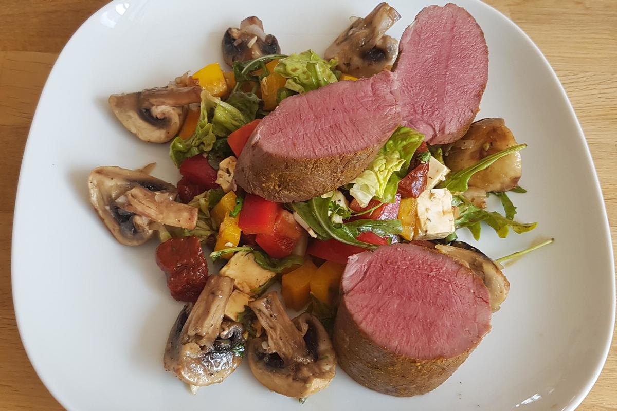 Pochierter Rehrücken mit gebratenen Champignons auf buntem Salat mit ...