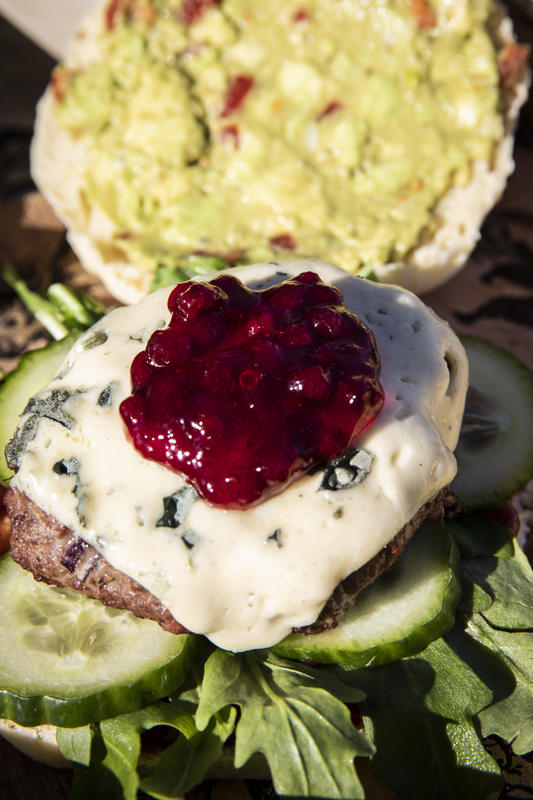 Und schon kann der Burger gebaut werden! Dazu die Buns aufschneiden und an der Innenseite leicht auf dem Grill antoasten. Die obere Hälfte mit Guacamole – die untere Hälfte mit Cranberry BBQ Sauce bestreichen, darauf den gewaschenen Rucola und die Salatgurkenscheiben platzieren. Patty mit dem geschmolzenen Blue Cheese obenauf geben. Nun das Ganze mit Preiselbeeren krönen. (Quelle: Czybik/DJV)