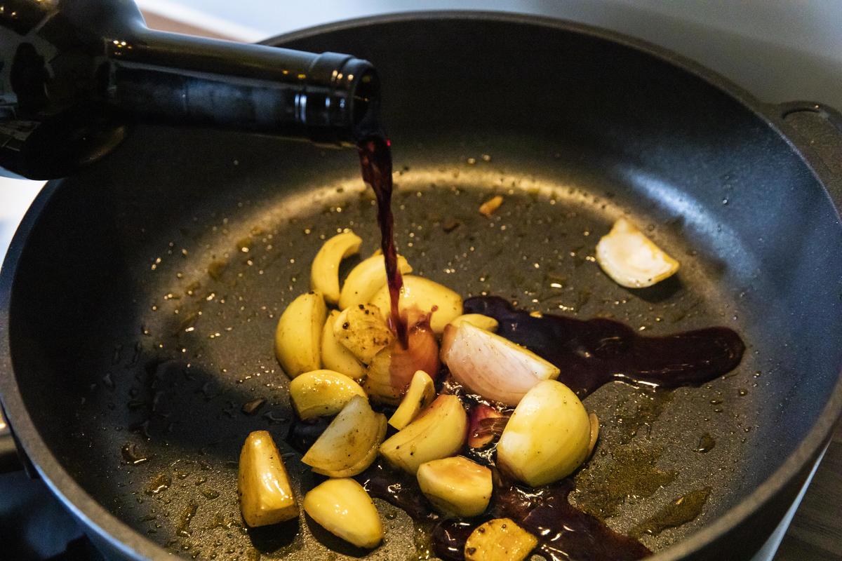 Für die Soße Zwiebeln und Knoblauch in eine Pfanne geben und kurz anbraten. Mit dem Wein ablöschen und der Brühe aufgießen. Alles kurz stark aufkochen, sodass die Flüssigkeit etwas reduziert wird.  (Quelle: Czybik/DJV)