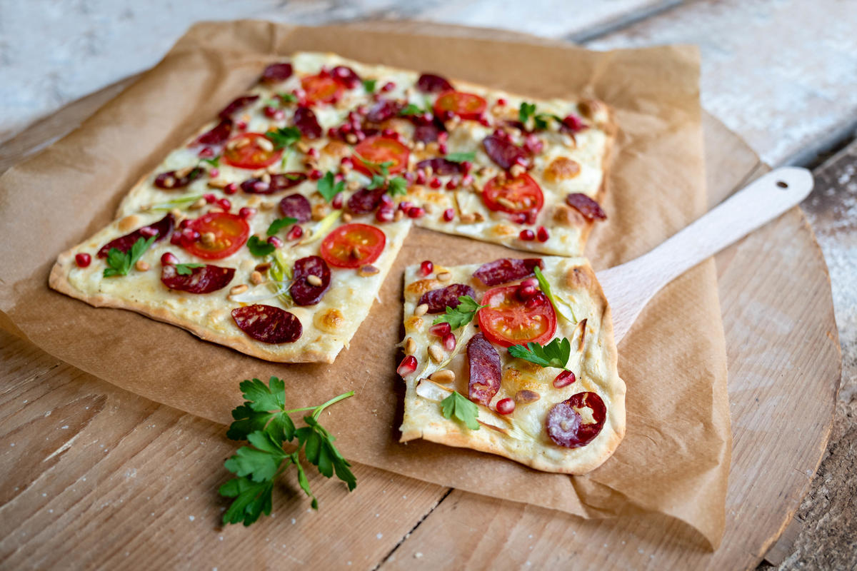Flammkuchen mit Pinien- und Granatapfelkernen bestreuen und mit Petersilie garnieren. (Quelle: Dorn/DJV)