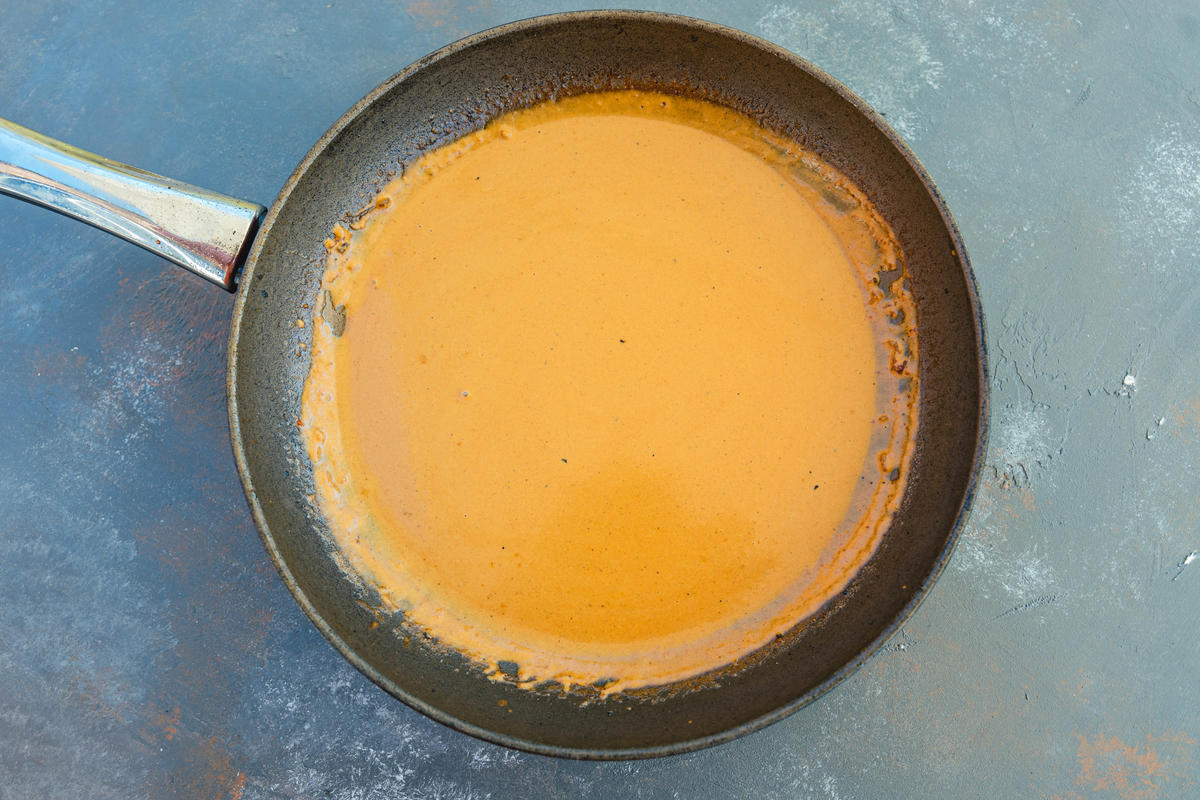 Den Bratensatz mit Sahne ablöschen, kurz aufkochen und mit Tomatenmark und Curry würzen. (Quelle: Dorn/DJV)