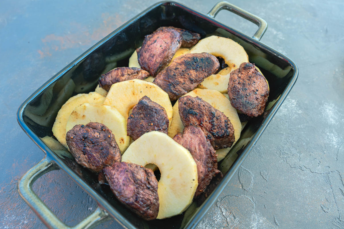 Apfelringe und Fleisch gleichmäßig verteilen. Sauce über das Fleisch gießen und zum Schluss geriebenen Käse darüber streuen.  (Quelle: Dorn/DJV)