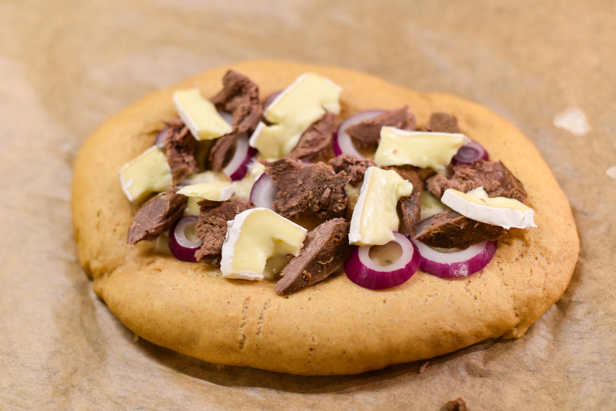 Den vorgebackenen Fladen mit Crème fraîche bestreichen, mit Camembert, Zwiebeln und Wildbret belegen. Weitere 7 bis 8 Minuten backen.  (Quelle: Kapuhs/DJV)