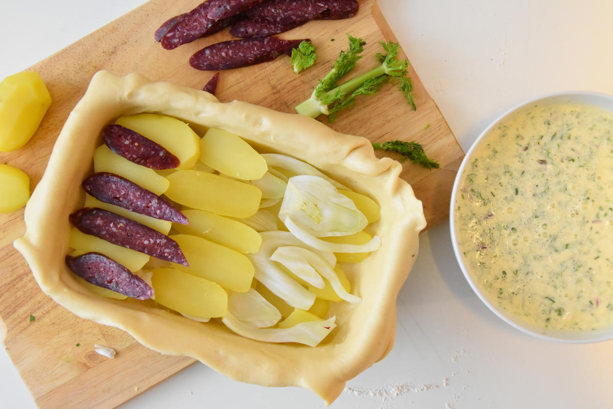 Vorgekochte Kartoffelscheiben, Fenchel und Knacker stapeln. Mit Guss auffüllen.  (Quelle: Kapuhs/DJV)