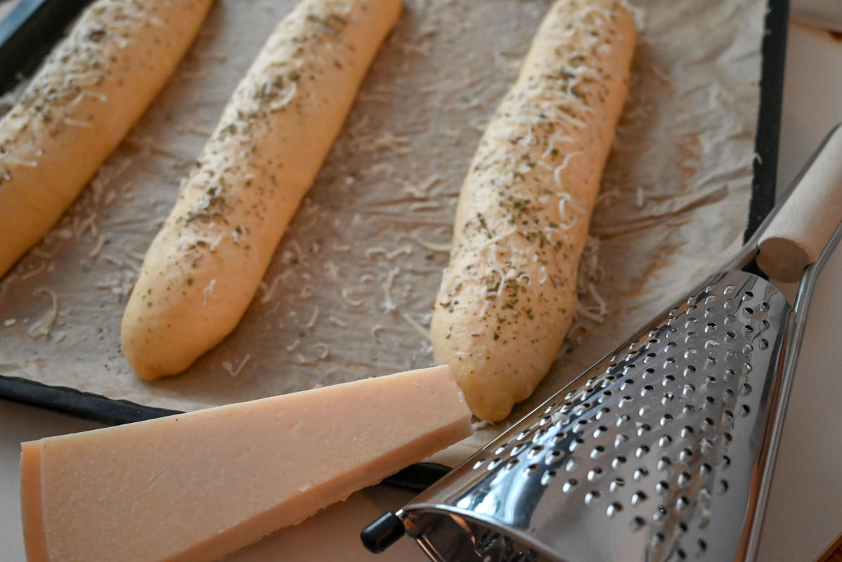 Den Teig zu länglichen Baguette formen, mit Oregano und Parmesan bestreuen.  (Quelle: Kapuhs/DJV)