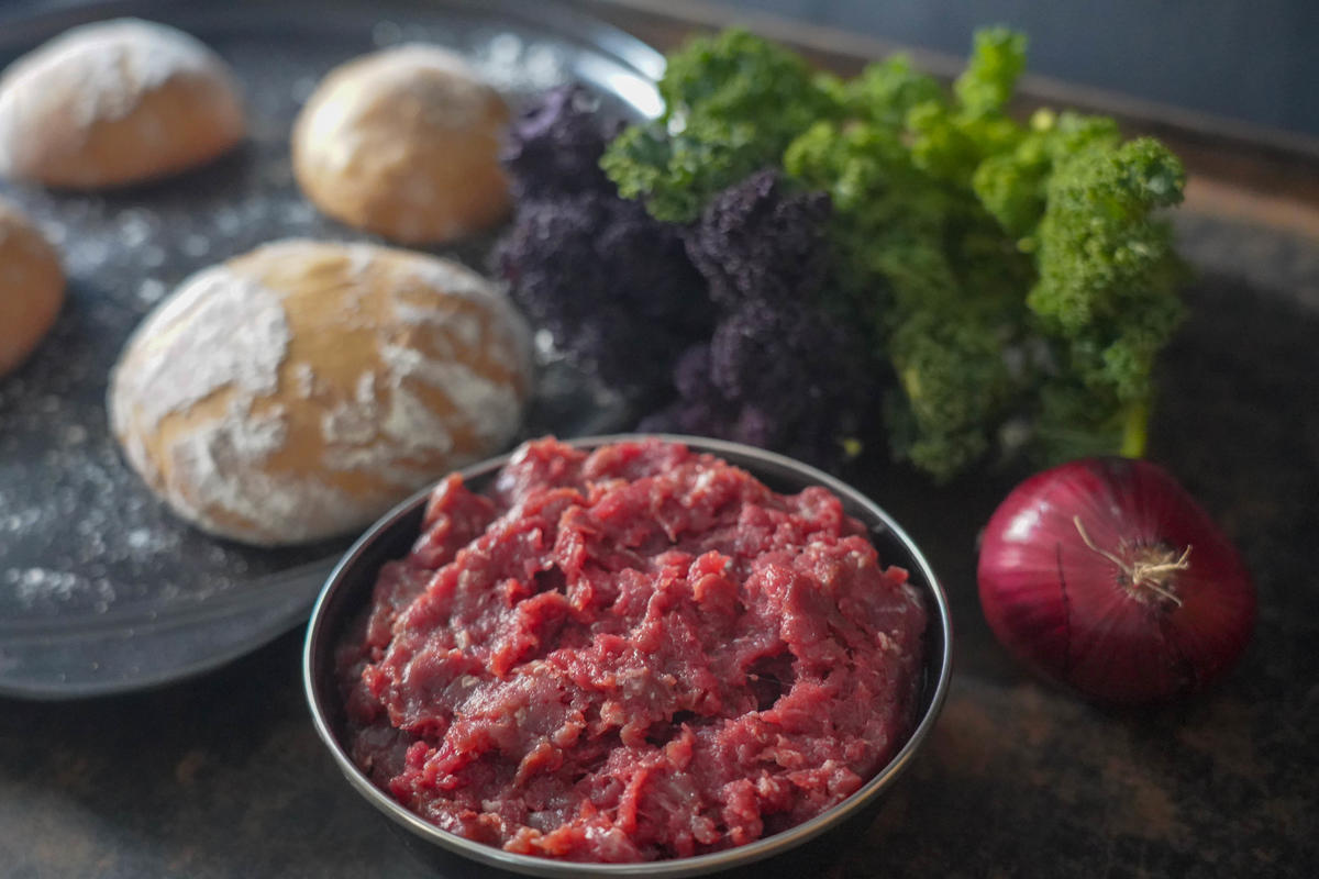 Die Hauptzutaten für das Rezept: Reh-Hackfleisch, Zwiebel, Grünkohl, Burger-Buns. (Quelle: Kapuhs/DJV)