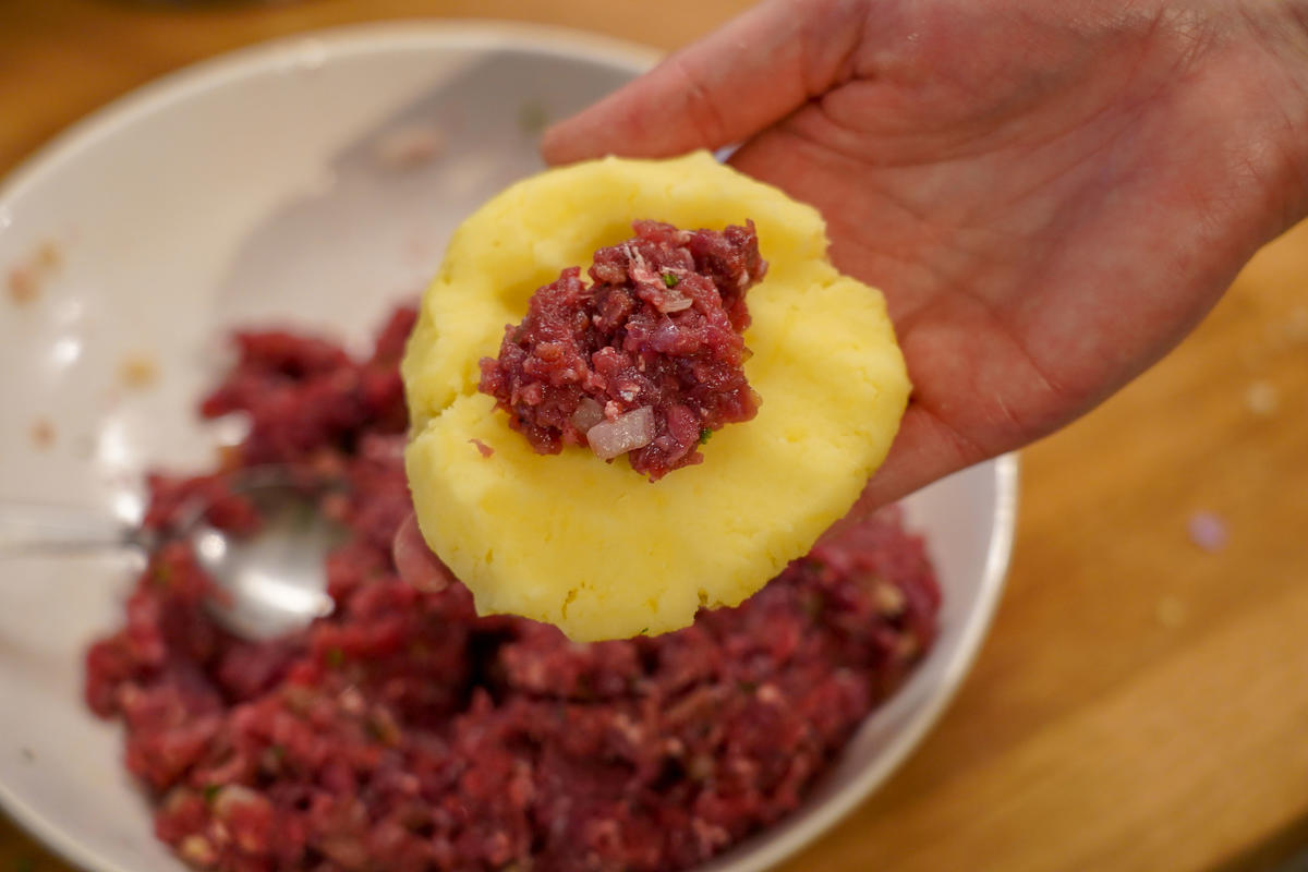 Den Teig mit dem Fleisch füllen und zu länglichen Klößen formen.  (Quelle: Kapuhs/DJV)