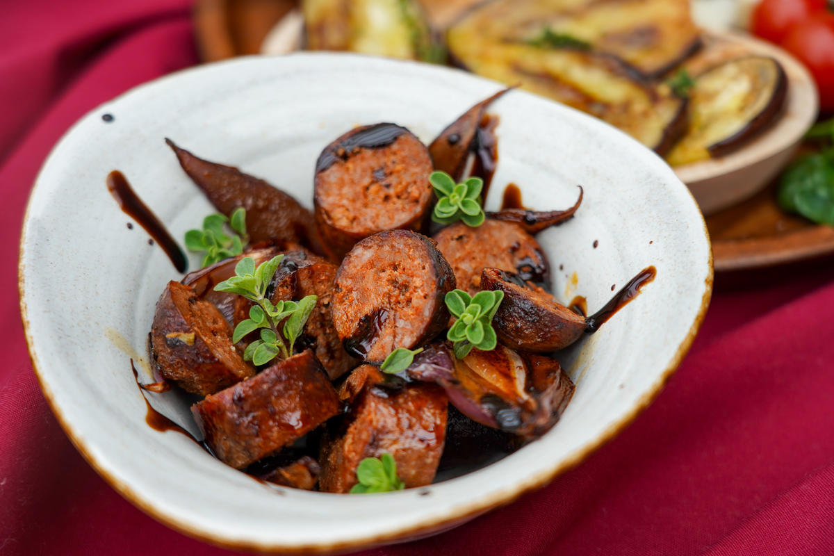 Die aufgeschnittenen Chorizo mit den Zwiebeln und einer Rotwein-Balsamico-Reduktion anrichten.  (Quelle: Kapuhs/DJV)